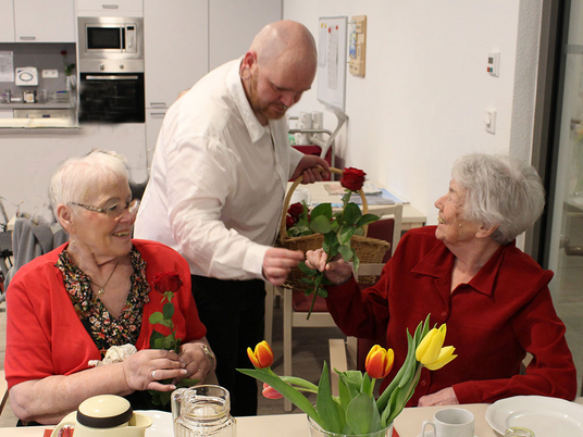 Betreuungsassistent Matthias Burmeister überreicht Rosen an Bewohnerinnen | Immanuel Seniorenzentrum Elstal